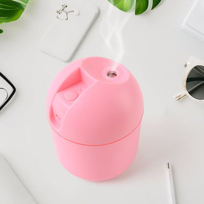 Pink USB mini air humidifier emitting mist on a stylish desk with plants and accessories