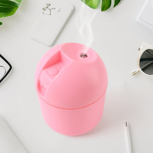 Pink USB mini air humidifier emitting mist on a stylish desk with plants and accessories