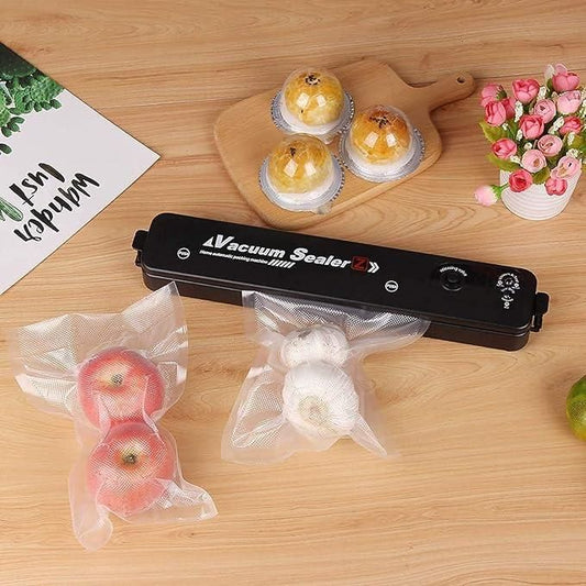 Vacuum sealer machine for food preservation with apples and garlic in vacuum bags on a wooden table