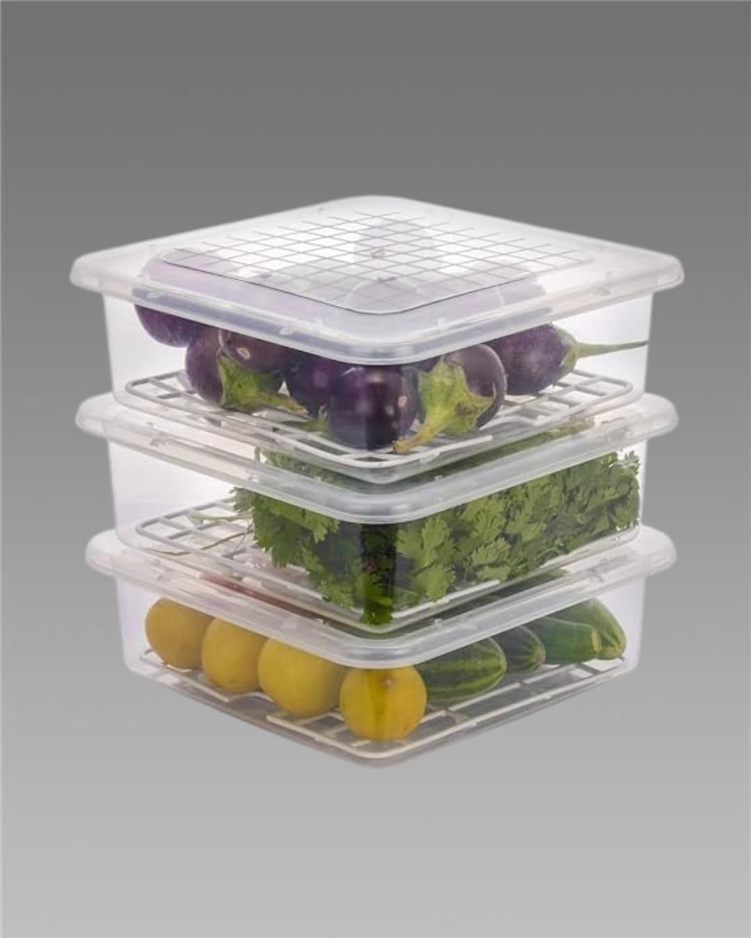 Stack of clear plastic fruit and vegetable containers holding eggplants, greens, and lemons