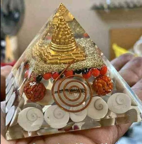 THE GIR FARMER crystal wealth pyramid for home with gold, red stones, and white spiral shells in clear resin