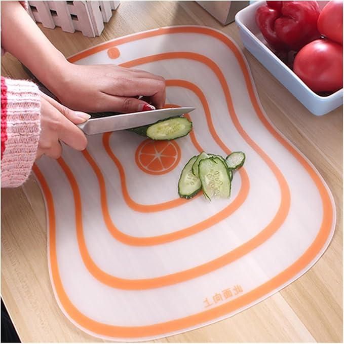 Flexible food prep board for vegetables with orange striped design being used to slice cucumber