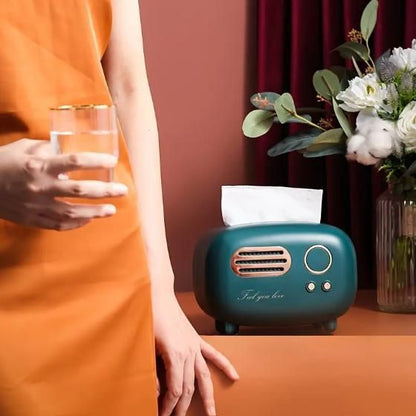 Vintage radio tissue box in teal with decorative flowers and a glass on a table