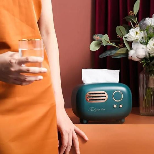 Vintage radio tissue box in teal with decorative flowers and a glass on a table
