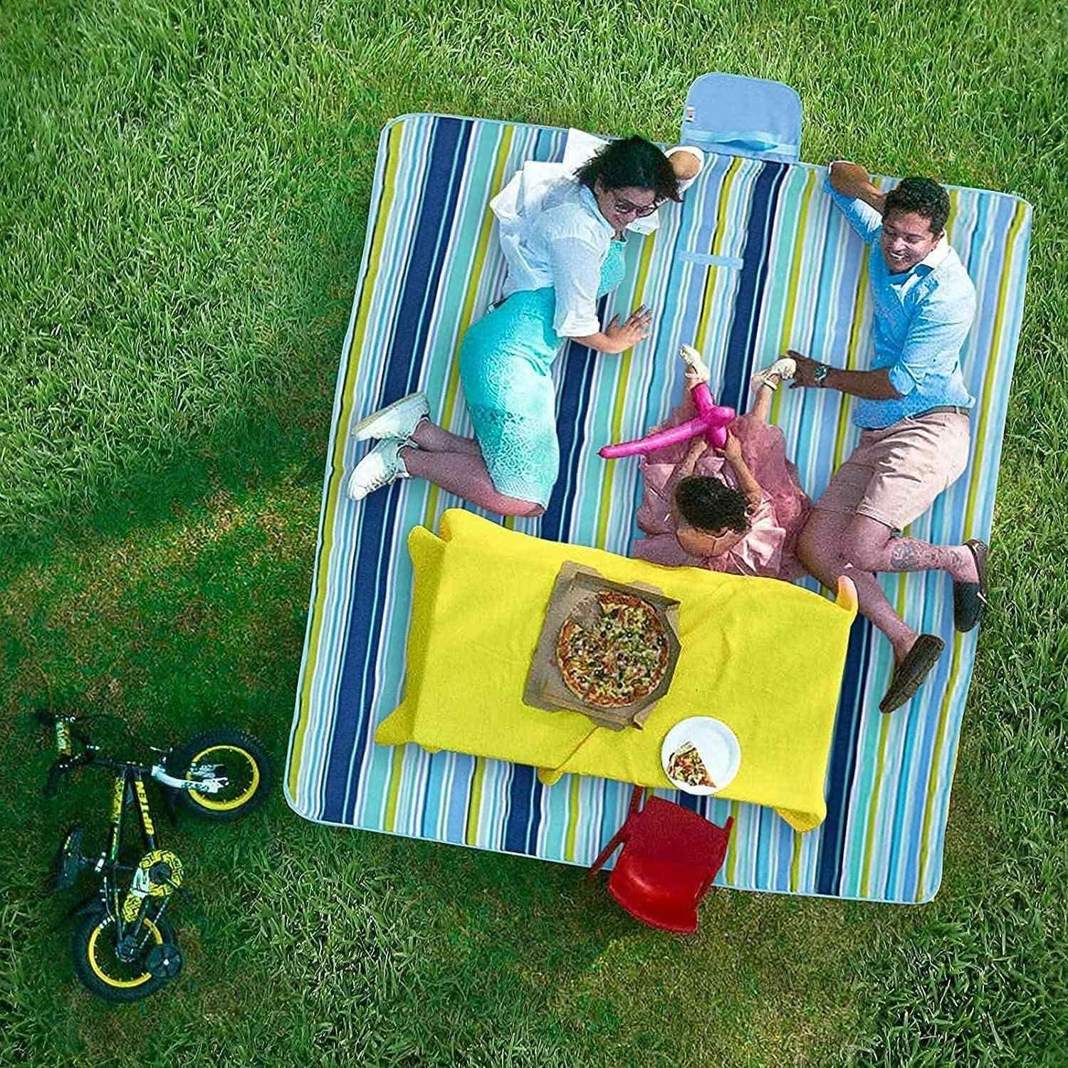 Family enjoying a meal on a colorful washable picnic mat in a grassy outdoor setting