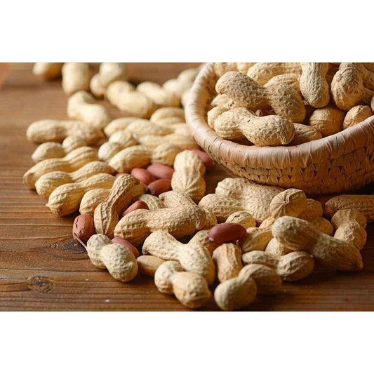 Basket of organic groundnuts with shell scattered on wooden table, perfect for snacking or cooking